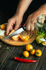 The chef hands cuts a tomato on a kitchen cutting board. Peasant food. Recipe for restaurant and hotel