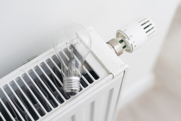 Energy crisis. light bulb on a radiator. electric and gas. Central heating.