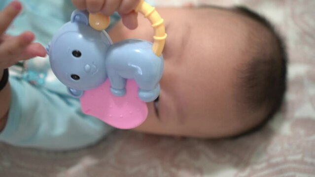 Close up head of cute infant put the teether toy into mouth