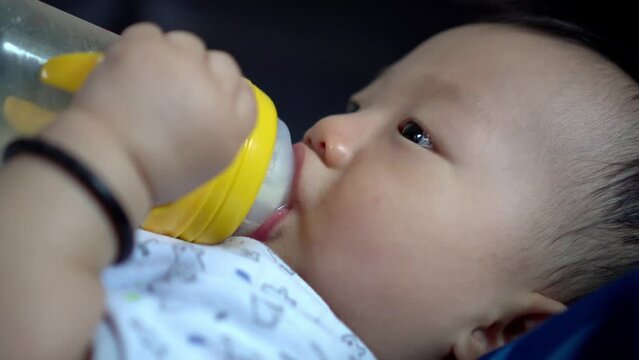 Close up the dace of baby boy hold the bottle drink milk