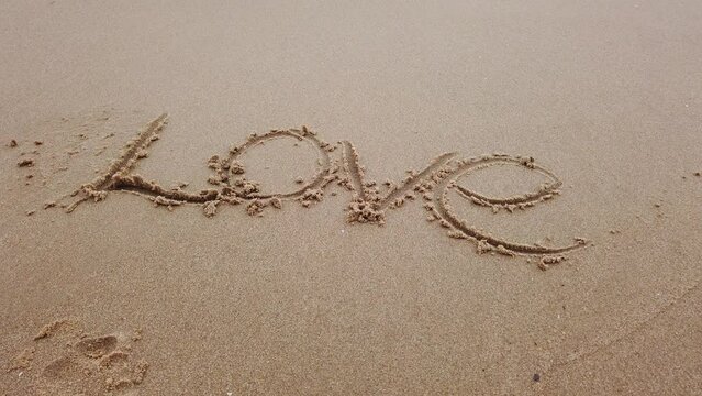 love word in sand in sea beach with ocean wave
