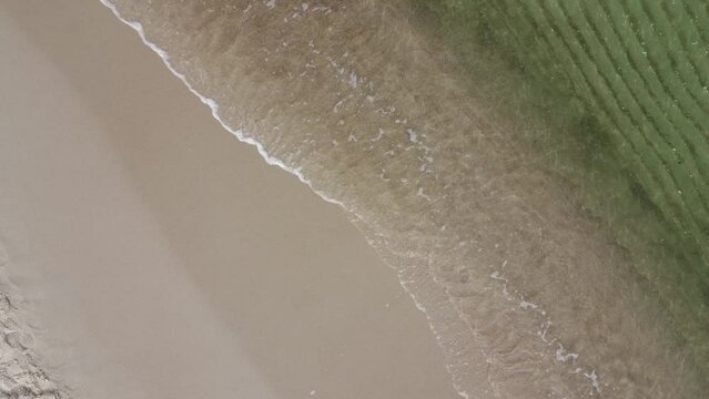 tiny ocean waves crashing on a sandy beach 