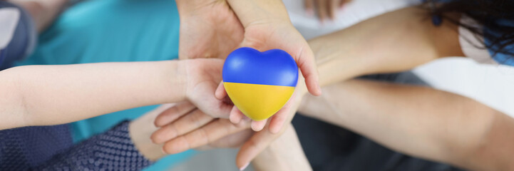 Group of people holding hearts with flag of Ukraine in their hands closeup top view