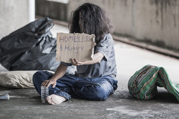 Homeless people sit on the streets in the shadows of buildings and ask for help and money the troubles of the big modern city.