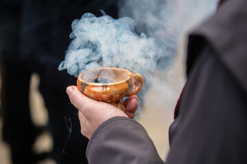 Closeup of the hand of an orthodox priest holding a censer, incense burner.