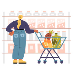 Woman with shoppping cart looking at shelves with goods in supermarket