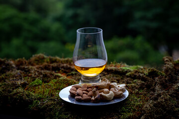 Single malt whiskey in a glen cairn glass over forest moss and cashews and almonds. blurred...