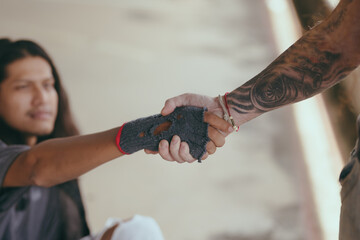 Close-up handshake homeless man on walkway street in the city., homeless poor people and depression concepts.