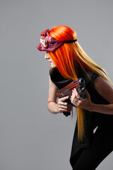 Cyborg mercenary in Asian demon mask, young woman with bright orange hair with a gun in her hands, futuristic cyber punk style