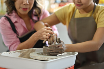 Close up with Pottery class where an elderly woman teaching students to make pottery from clay.