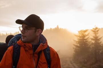a man with a large tourist backpack at sunrise against the backdrop of mountains and forests landscape tourism travel hiking hiking trekking