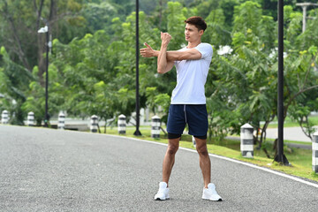 Full length man warming up, stretching her arms before morning workout. Fitness, sport and healthy lifestyle concept