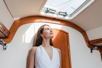 Young woman inside boat looking up through window