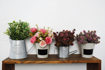 Artificial flowers bouquet in metal vase on wooden shelf interior decoration