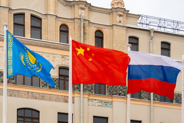 View of the flags of China, Russia, and Kazakhstan on a background of building