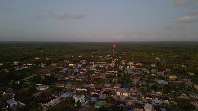 Radio communications tower and town of Uroa Beach in Zanzibar Tanzania Africa, Aerial orbit around shot