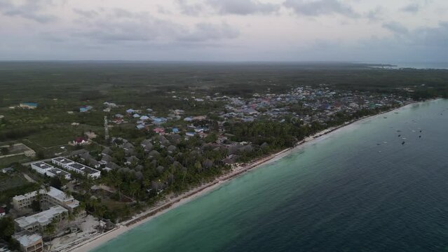 Uroa beach town with resorts and homes in Zanzibar Island, Tanzania Africa, Aerial dolly out shot