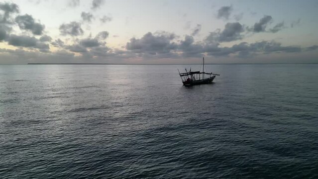 Boat floating near Uroa beach in Zanzibar Island, Tanzania Africa during sunset, Aerial pan right shot