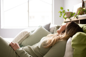 woman  lying on bed while looking at window with green and white pillows