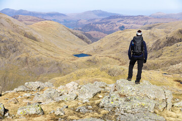 Hiker looks at view from close to Scafell Pike summit in Lake District