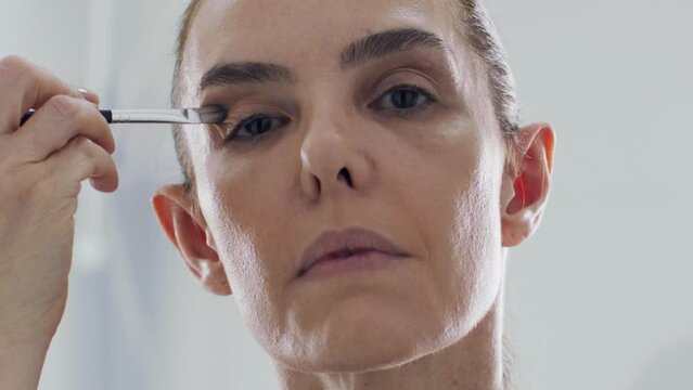 Mature Woman Applies Eyeliner And Eye Shadow, Slow Motion Face Closeup. 