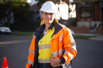 Close up shot of a woman road worker with white helmet and orange jacket with a silver reflector