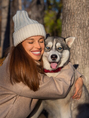 Young woman embracing her dog, a husky. Close-up vertical photo.