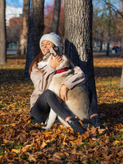 Young woman embracing her dog, a husky - vertical photo.