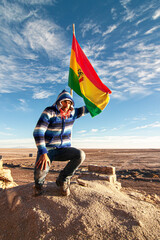 Man next to Bolivian flag in Salar de uyuni