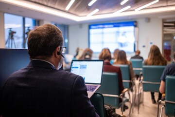 Businessman with laptop taking photos during conference