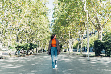 Determined and successful young woman walking in the city park