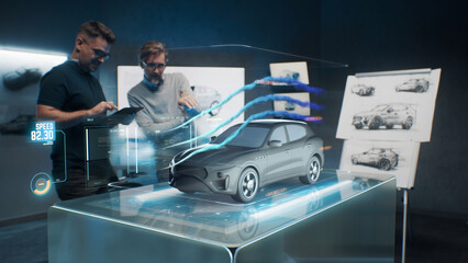 Car design engineers using holographic app in digital tablet. Develop modern innovative high-tech cutting edge eco-friendly electric car with sustainable standards. They test the aerodynamic qualities - obrazy, fototapety, plakaty