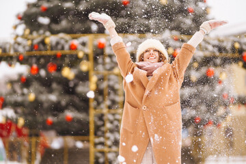 Young happy woman outdoor during christmas time in front of christmas lights. Holidays, rest, travel concept.
