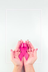 Pink ribbon background. Health care symbol pink ribbon in woman hands on white background. Breast cancer support concept. World cancer day.