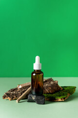 Oil with Serum for Skin and Hair Care Concept of Essential Oil Tree Bark with Moss Stone and Wooden Sticks on a Green Background Vertical