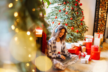 Young  woman having video call  by christmas tree at home. Christmas online holiday. 