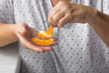 Senior woman's hands holds yellow hydrogel eye patches in front of her, ready for use. Elderly lady using cosmetics.