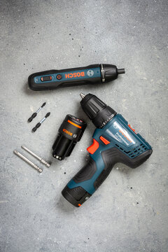 Electric screwdrivers with bits and a rechargeable battery on the table. Bosch hand tool on a gray background top view. Created on february 21, 2021 in Moscow, Russia