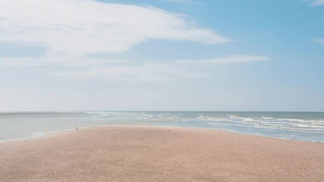 Cinemagraph of sandy beach and moving waves with blue cloudy sky
