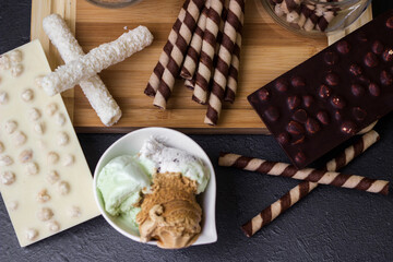 Sweet table with chocolate waffles, chocolate and ice cream on a black background. Waffle rolls