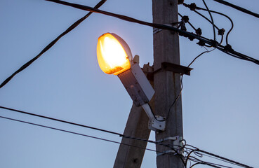 A lantern on a pole shines at sunset.