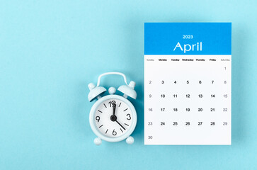 The April 2023 Monthly calendar for 2023 year with vintage alarm clock on blue background.