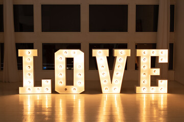 Love big white letters with led retro bulbs glowing. Word LOVE with a big letters. Inscription is...