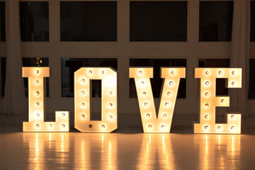 Love big white letters with led retro bulbs glowing. Word LOVE with a big letters. Inscription is love. Glowing large letters. Wedding decor. Illuminated Love sign in large letters near window. 