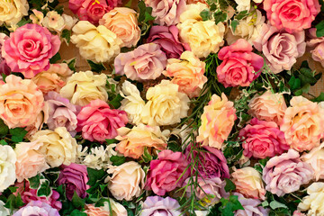 Closeup Interior floral wedding party decor. Wall with curly Flowers. Wall with beautiful flowers. Summer flowers on wall building. Beautiful decorative colorful roses and peonies on brick white wall	