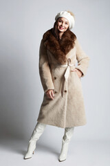 Happy young woman in fur and Hat. beautiful bruhette girl in trendy winter fashion coat