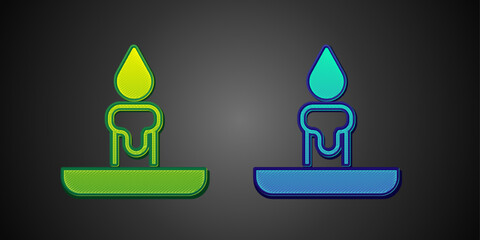 Green and blue Burning candle in candlestick icon isolated on black background. Cylindrical candle stick with burning flame. Vector