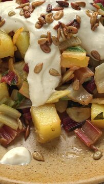 Croatian Blitva (swiss chard with potato, garlic and olive oil) dressed with yoghurt - tahini sauce and roasted sunflower seeds. Vertical video.