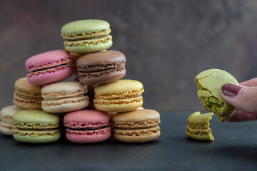 stack of macaroons and woman hand holding a cookie