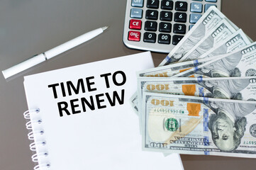 TIME TO RENEW text on paper on the table next to a calculator, dollars and a pen
